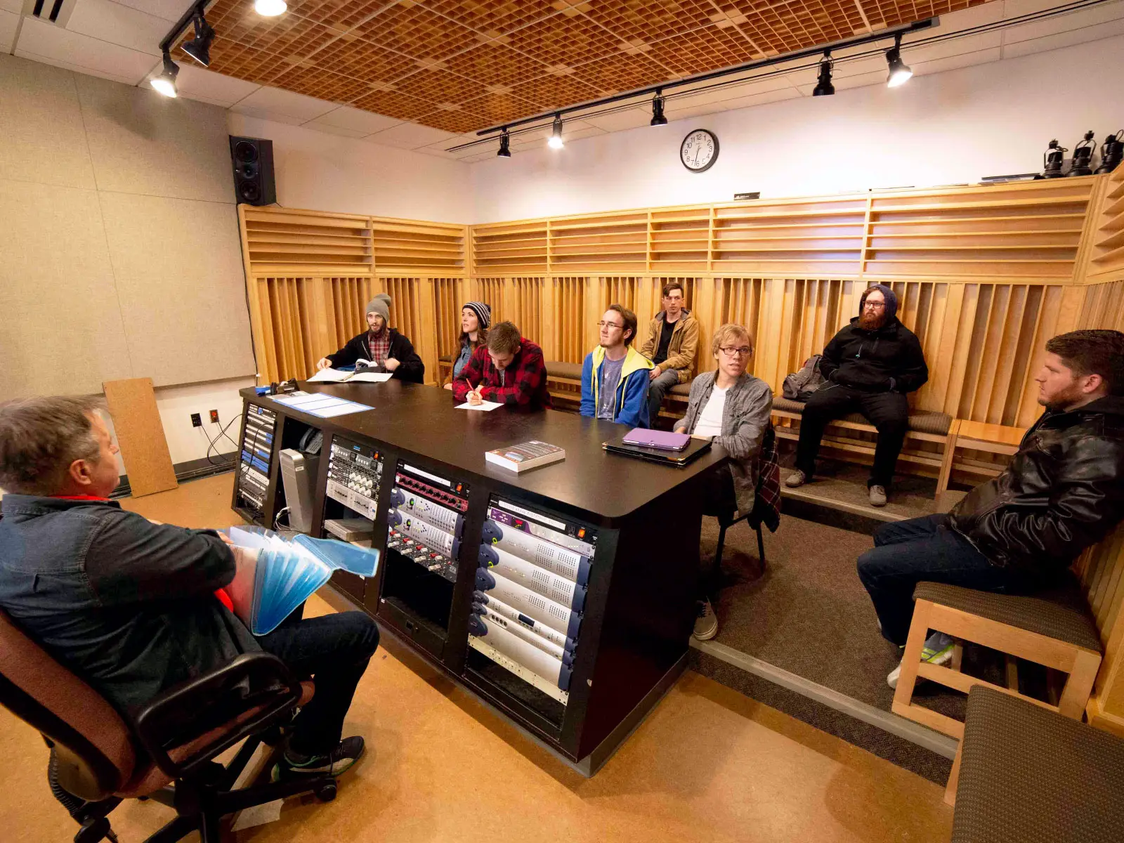 Students sitting around audio computer hardware, taking notes during an instructor's lecture in Niemeyer Center